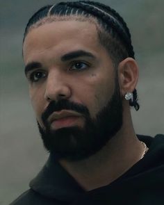 a man with dreadlocks wearing a black hoodie and looking at the camera