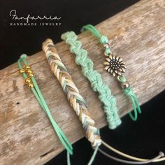 three different bracelets are sitting on a piece of wood and one is made out of rope