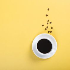 a cup of coffee and some seeds on a yellow background