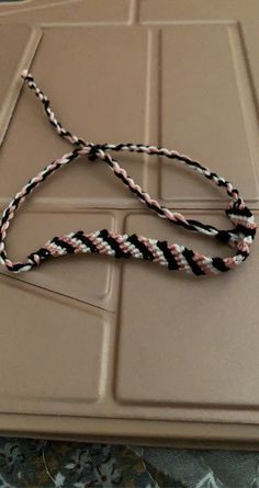 a black, white and pink rope on top of a brown tray with an object in the background