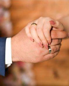 two people holding hands while one holds the other's hand with their wedding ring