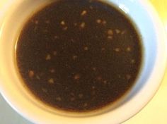 a white bowl filled with brown liquid on top of a table