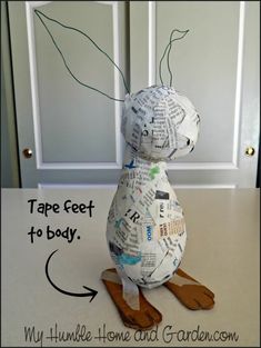 a cat made out of newspaper sitting on top of a wooden board with the words tape feet to body