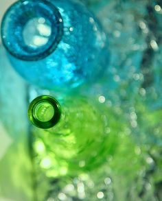 two blue and green bottles sitting on top of each other