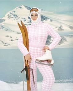 a woman in pink and white snow suit holding skis