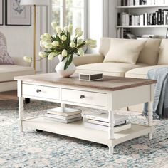 a white coffee table with flowers in a vase on top