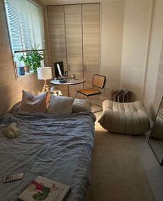 a bedroom with a bed, chair and desk in it's corner area next to a window