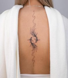 the back of a woman's neck with a fish tattoo on her left side