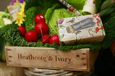 a basket filled with lots of vegetables next to a sign that says heathcote & ivory