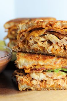 two sandwiches stacked on top of each other next to a small bowl of dipping sauce