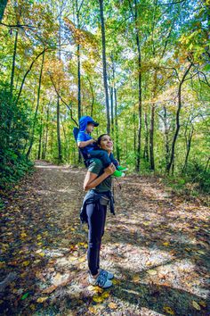 a woman carrying a child on her back in the woods