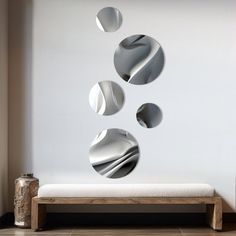 three circular mirrors on the wall above a bench in front of a white wall and floor