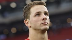 a close up of a person wearing a red shirt and looking off into the distance