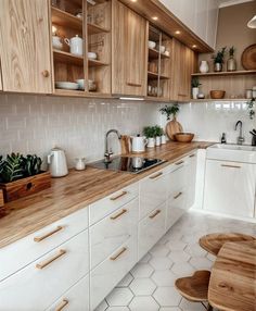 a kitchen with white cabinets and wooden counter tops, along with potted plants on the shelves