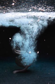 an underwater photo of a bird in the water with bubbles coming out of its beak