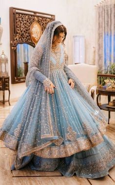 a woman in a blue bridal gown standing on the floor with her hands behind her head