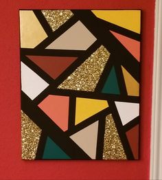 an abstract painting on a red wall with gold glitters and black, orange, yellow, pink, and green triangles