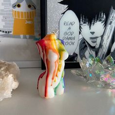 a colorful candle sitting on top of a table next to a crystal bowl and painting