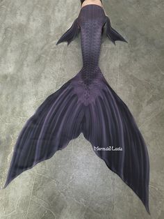 a woman is laying on the floor with a purple mermaid tail and long black hair