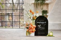 flowers are in a vase next to an unplugged gravestone and plaque