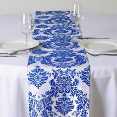 a blue and white damask table runner on a dining room table with wine glasses