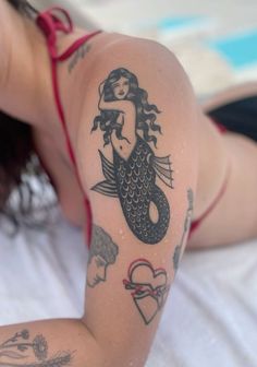 a woman laying on top of a bed with tattoos on her arm and chest,