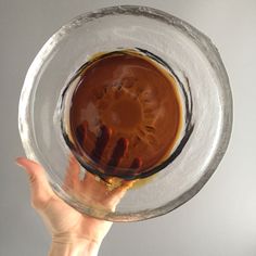 a person holding up a glass bowl with liquid in it and their hand on the bottom