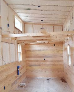 an unfinished room with wood walls and windows