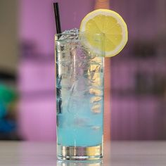 a glass filled with blue liquid and a lemon slice