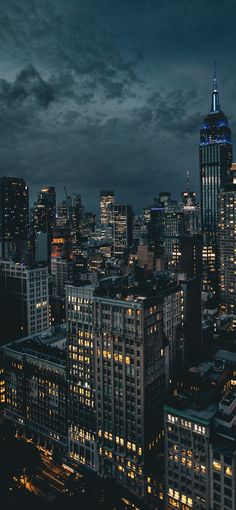 the city skyline is lit up at night, with skyscrapers in the foreground