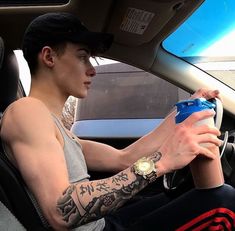 a man sitting in the driver's seat of a car with tattoos on his arm