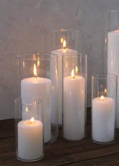 white candles in glass vases on wooden table