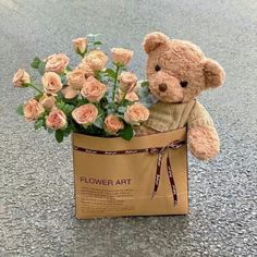 a teddy bear sitting in a bag with flowers