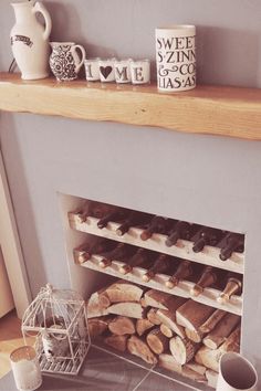 a fireplace with logs and mugs on the mantle