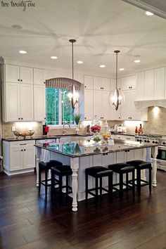 a large kitchen with white cabinets and wooden floors