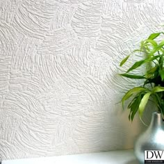 a potted plant sitting on top of a white shelf next to a wall paper