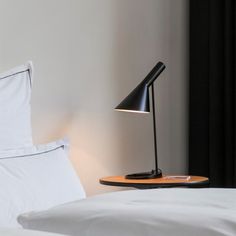 a bed with white pillows and a black lamp