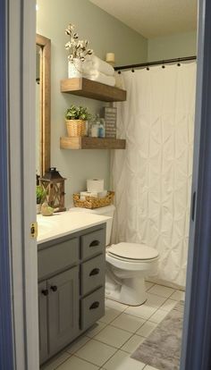 a white toilet sitting next to a bathroom sink under a mirror and shelves above it