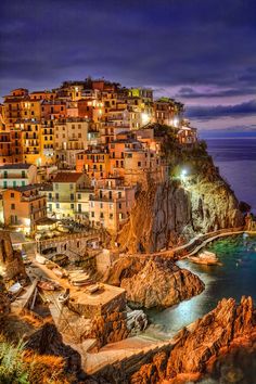 the town is lit up at night on top of a cliff overlooking the ocean and beach