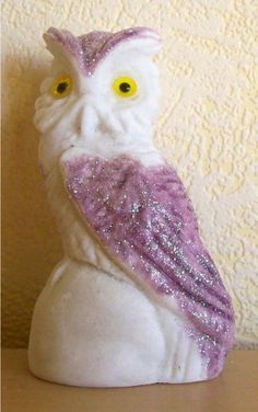 a white and purple owl statue with yellow eyes