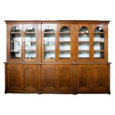 an old wooden china cabinet with glass doors on the top and bottom, against a white wall