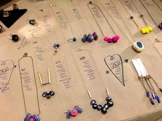 a table topped with lots of different types of necklaces on display next to each other