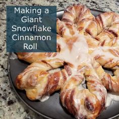 a black plate topped with cinnamon rolls covered in icing on top of a counter