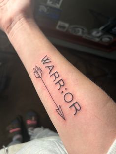 a person with a tattoo on their arm that says warrior and an arrow in the middle