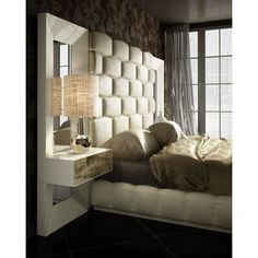 a bedroom with a bed, mirror and lamp on the side table in front of it