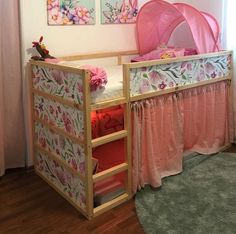 there is a baby crib in the room with pink curtains and flowers on it