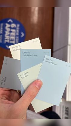 a person holding up some paint samples in their hand, with the color swatches on them