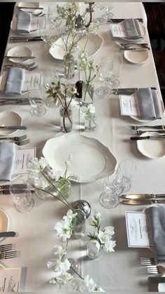 the table is set with silver and white plates, napkins, and flowers in vases