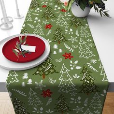 a green table cloth with christmas trees on it and a red plate next to it