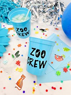 blue cups with zoo crew on them and confetti scattered all over the table